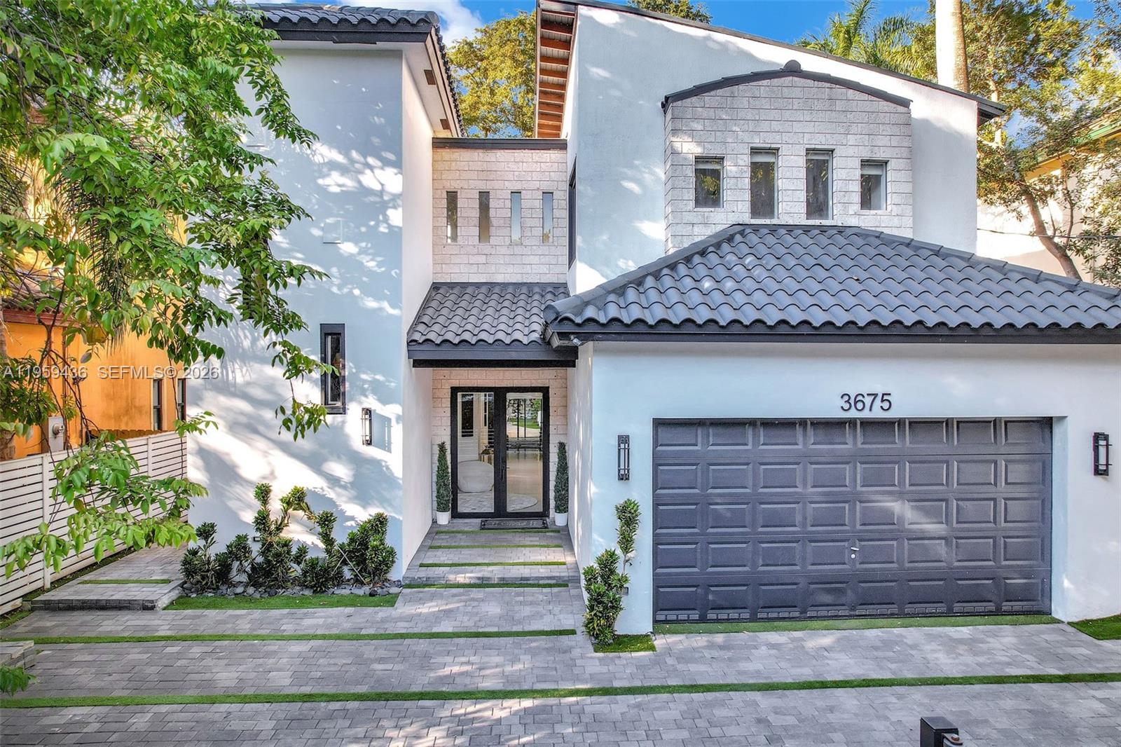 A modern two-story house features a gray garage, a tiled roof, and a stone-accented entrance — 3675 Loquat Ave, Miami FL 33133, MIAMI, FL