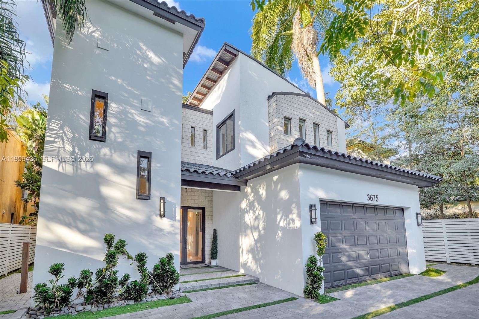 A two-story house features white stucco walls, a gray garage door, and a tiled roof — 3675 Loquat Ave, Miami FL 33133, MIAMI, FL