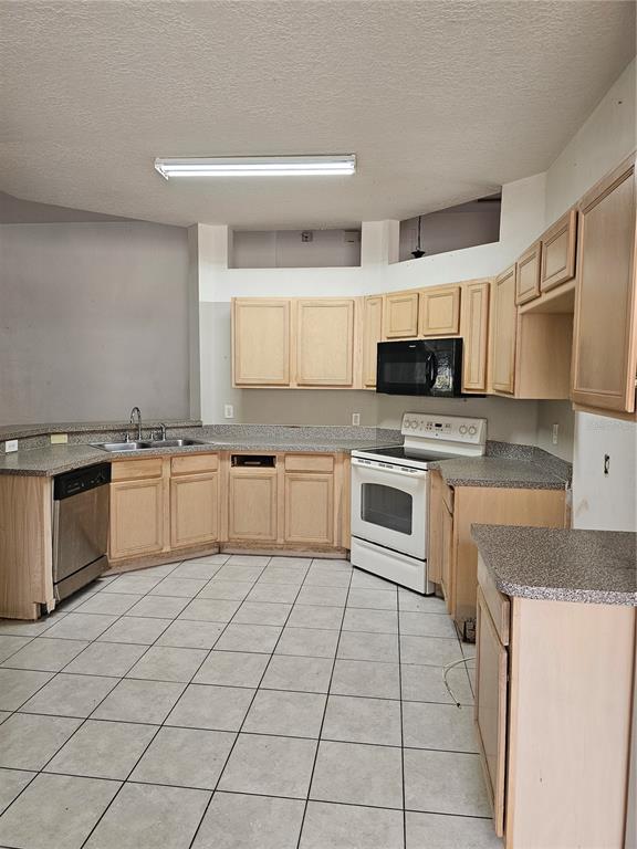 A kitchen with light wood cabinets, gray countertops, white appliances, and a tiled floor — 704 EOLA WAY, HAINES CITY, FL