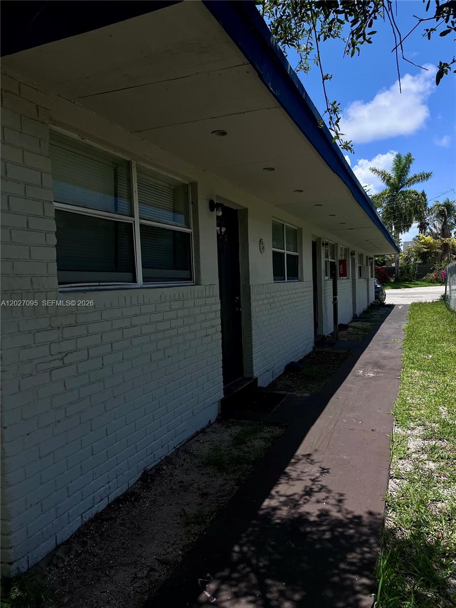 A side view of a single-story white brick building with a concrete walkway — 109 NW 14th Way # 3, Dania Beach FL 33004, DANIA BEACH, FL