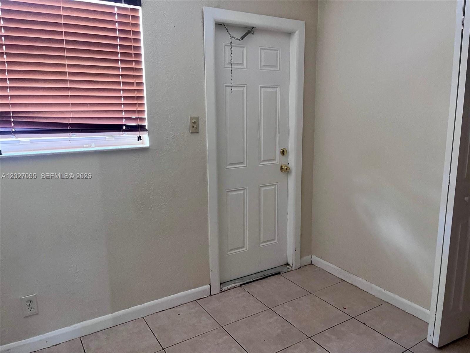 A room with tiled flooring, a white door with a chain lock, and a window — 109 NW 14th Way # 3, Dania Beach FL 33004, DANIA BEACH, FL