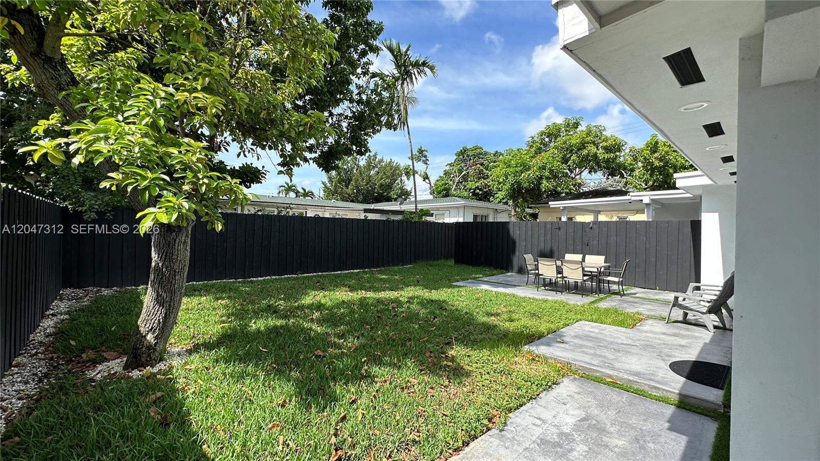 A backyard features a grassy lawn, a concrete patio with outdoor furniture, and a black fence — 4288 SW 9th St # 1, Miami FL 33134, MIAMI, FL