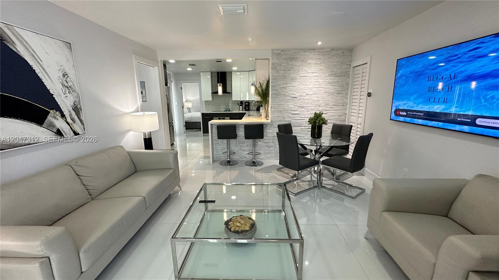 A modern living room features white tile floors, a glass coffee table, and a kitchen bar — 4288 SW 9th St # 1, Miami FL 33134, MIAMI, FL