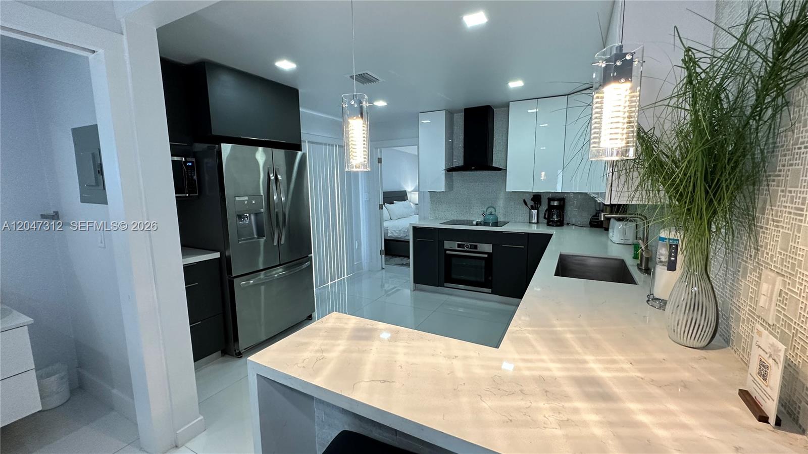 A modern kitchen features dark lower cabinets, white upper cabinets, and a quartz countertop peninsula — 4288 SW 9th St # 1, Miami FL 33134, MIAMI, FL