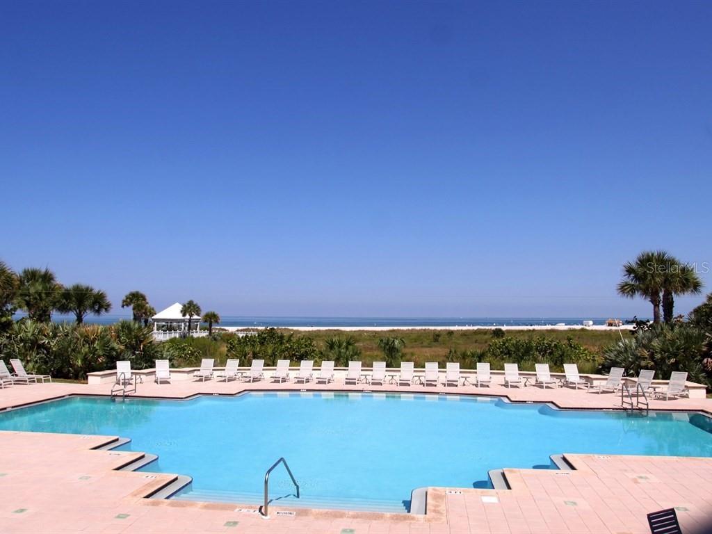 A swimming pool sits on a patio overlooking a sandy beach and the ocean — 1180 GULF BOULEVARD UNIT 606, CLEARWATER BEACH, FL