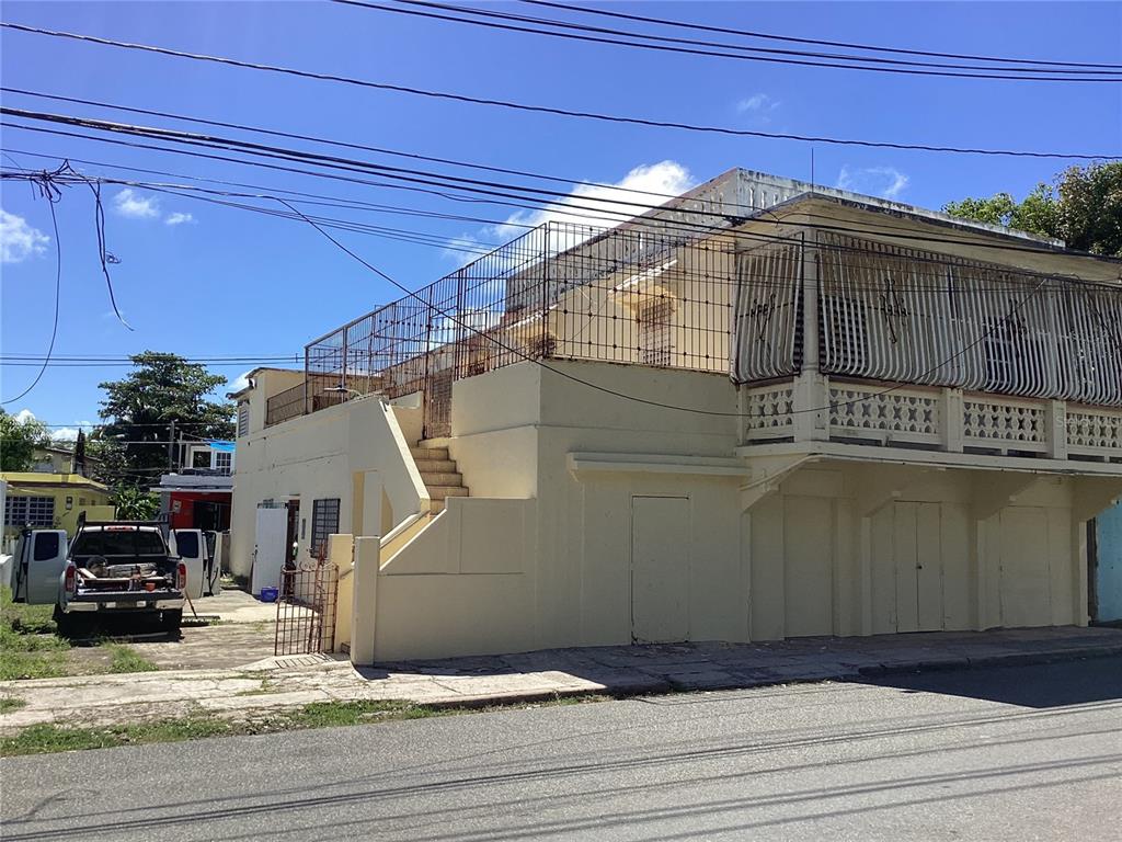 A two-story yellow building features an exterior staircase leading to a fenced upper terrace — Calle Union PLAYA PUERTO REAL UNIT 454, FAJARDO, PR