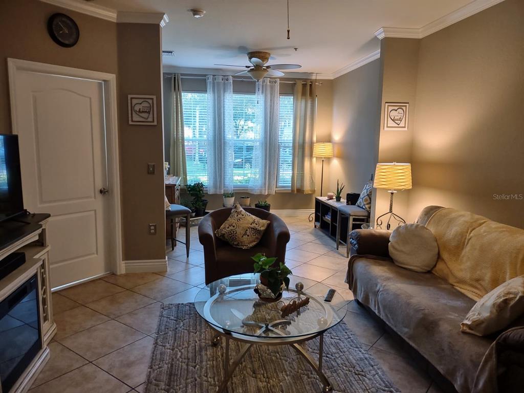 A living room features tile flooring, a ceiling fan, a glass coffee table, and windows — 2721 VIA MURANO UNIT 311, CLEARWATER, FL
