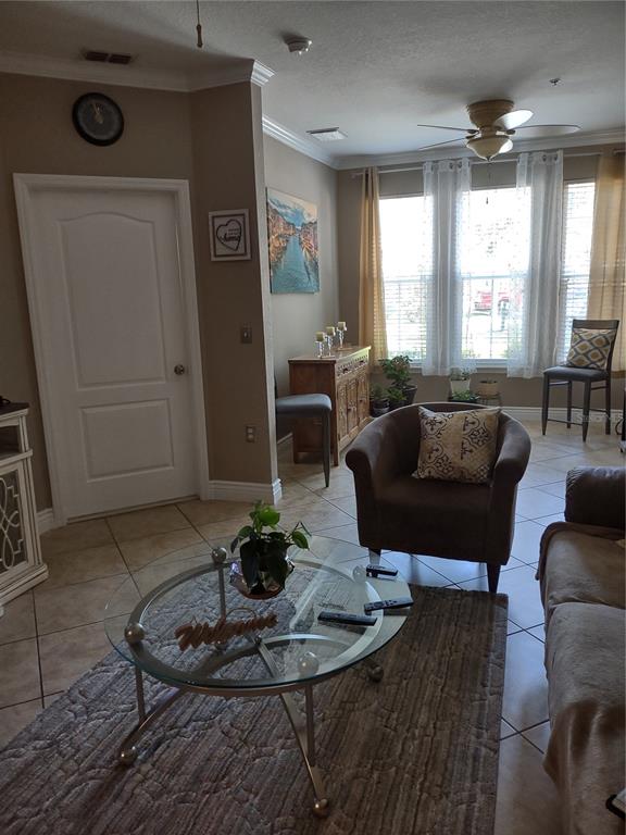 A living room features tile flooring, a glass coffee table, an armchair, and large windows — 2721 VIA MURANO UNIT 311, CLEARWATER, FL