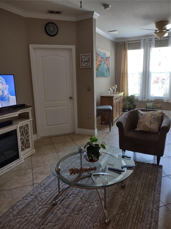 A living room features a glass coffee table, an armchair, and a fireplace media console — 2721 VIA MURANO UNIT 311, CLEARWATER, FL