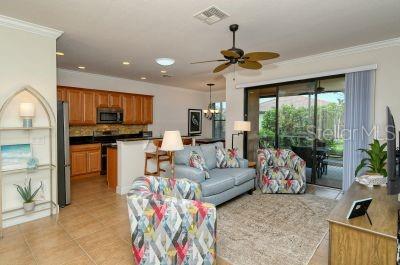An open-concept living room and kitchen with tile flooring, wooden cabinets, and glass sliding doors — 20405 CAVALLO COURT, VENICE, FL
