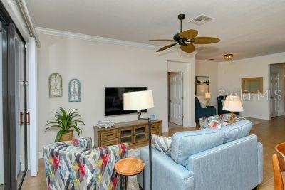 A living room features a television, a ceiling fan, a blue sofa, and patterned armchairs — 20405 CAVALLO COURT, VENICE, FL