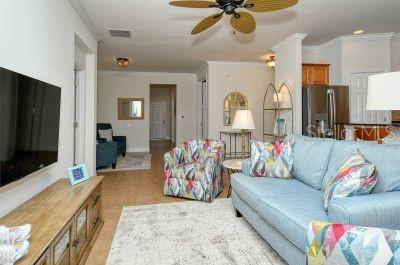 A living room features a blue sofa, patterned armchair, television, and ceiling fan — 20405 CAVALLO COURT, VENICE, FL