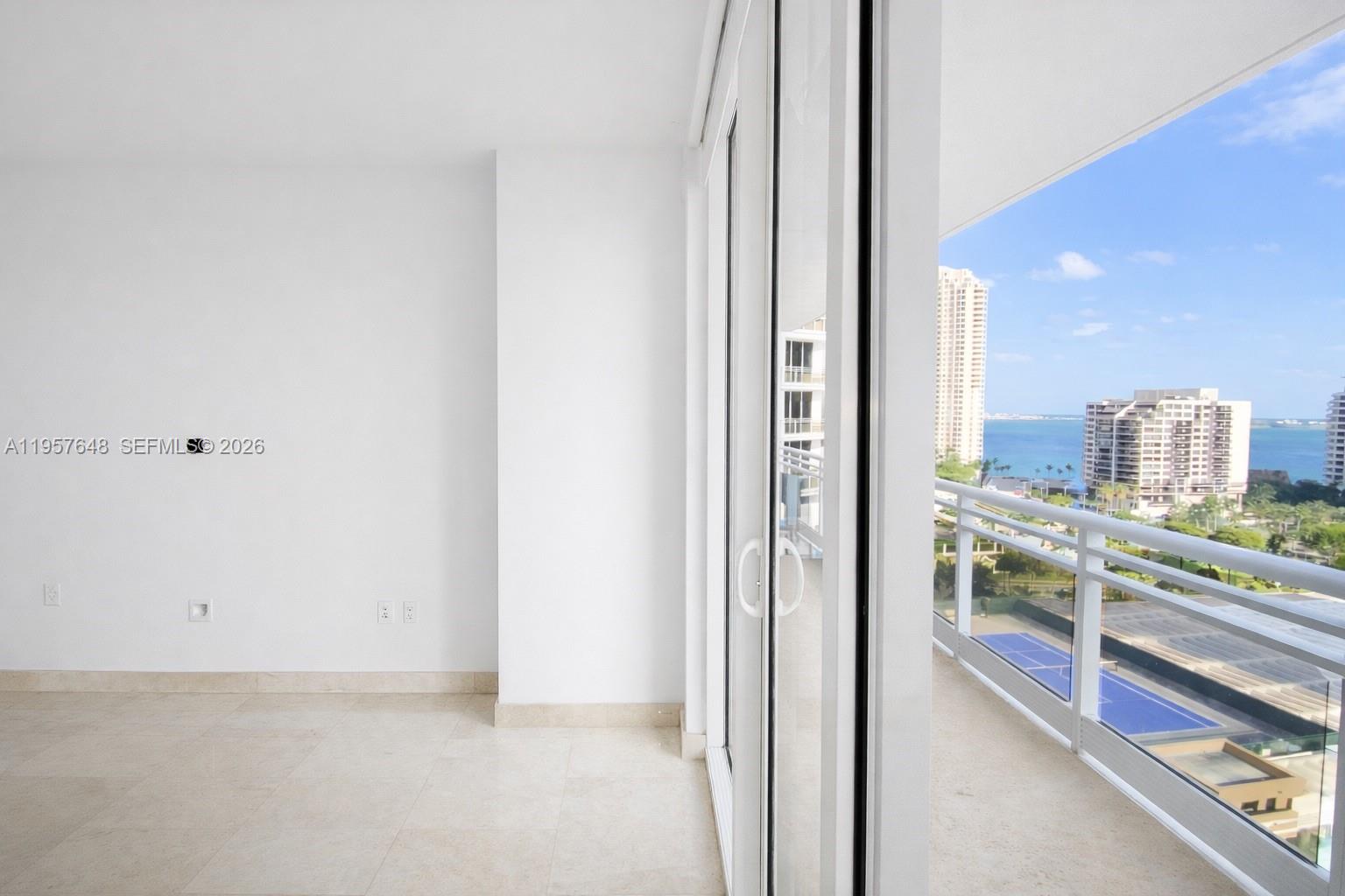 An empty room with white walls, tile floors, and a sliding door leading to a balcony — 901 Brickell Key Blvd # 1603, Miami FL 33131, MIAMI, FL