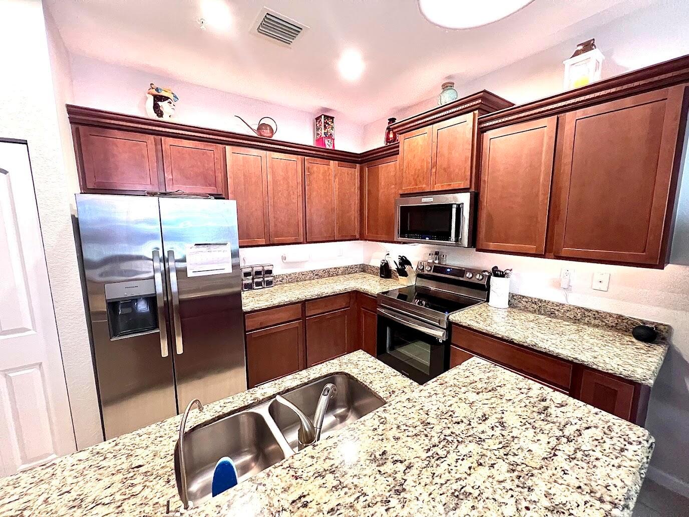 A kitchen features wood cabinets, granite countertops, stainless steel appliances, and a central island sink — 726 SW 1st Way, Pompano Beach FL 33060, POMPANO BEACH, FL
