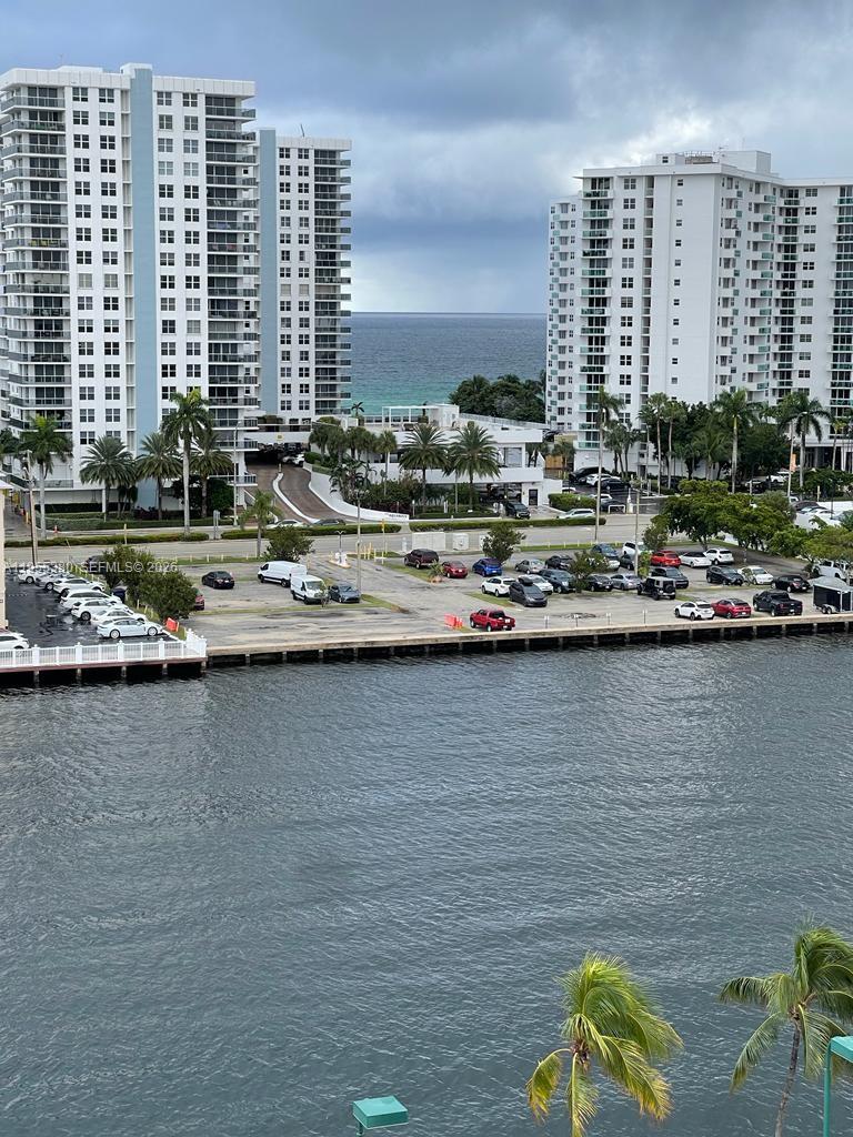 An exterior view shows a waterfront parking lot between two tall residential apartment buildings — 1000 Parkview Dr # 1016, Hallandale Beach FL 33009, HALLANDALE BEACH, FL