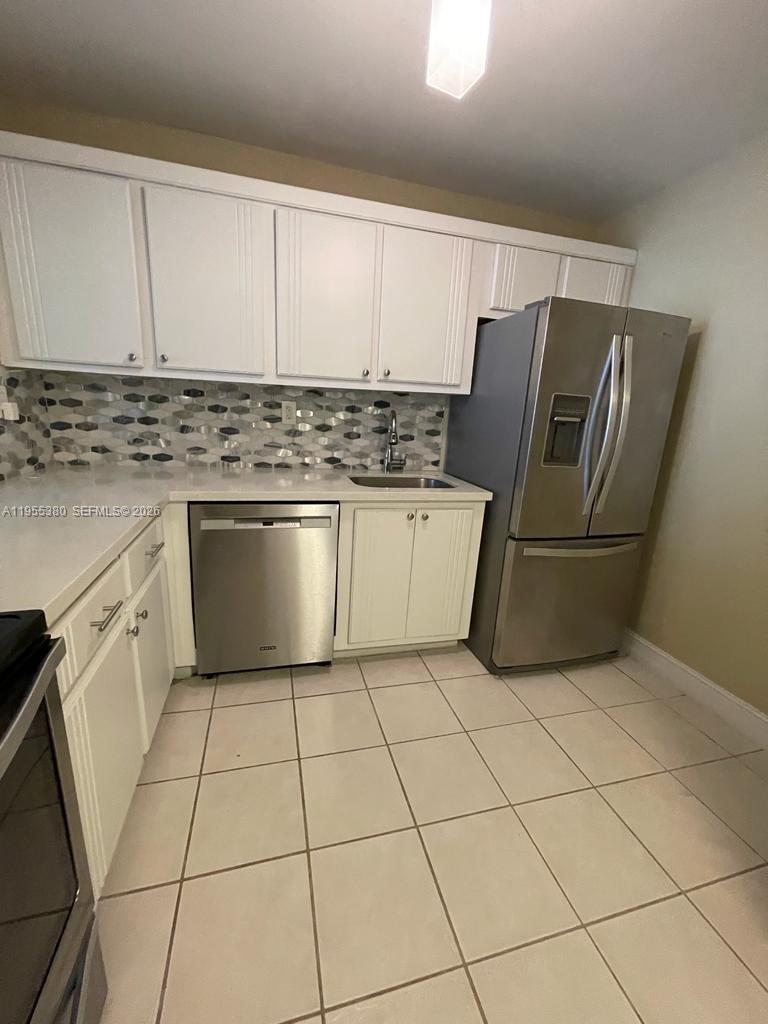 A kitchen features white cabinets, stainless steel appliances, a tiled backsplash, and light-colored floor tiles — 1000 Parkview Dr # 1016, Hallandale Beach FL 33009, HALLANDALE BEACH, FL