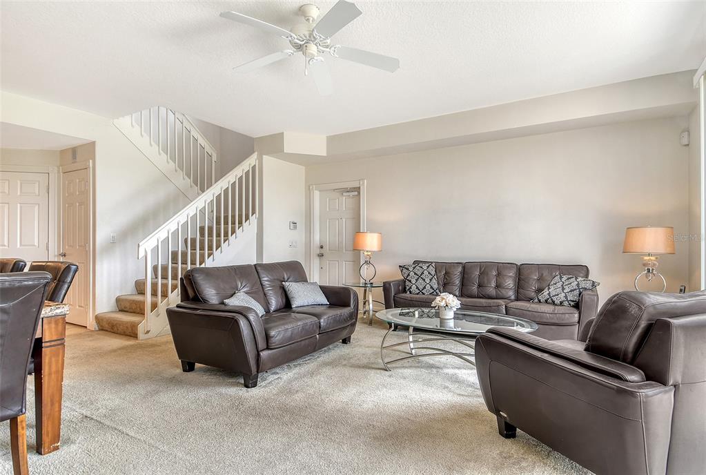 A living room features brown leather furniture, a glass coffee table, and a carpeted staircase — 1400 BURGOS DRIVE, SARASOTA, FL
