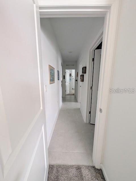 A hallway with light-colored tile flooring leads to a doorway at the end — 2860 BIG SUR ROAD, DAVENPORT, FL