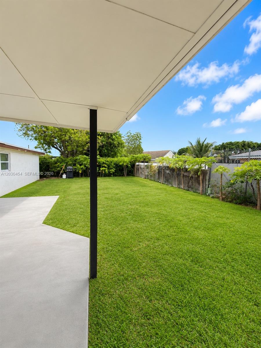 A view of a grassy backyard from under a covered patio — 20600 SW 118th Pl, Miami FL 33177, MIAMI, FL