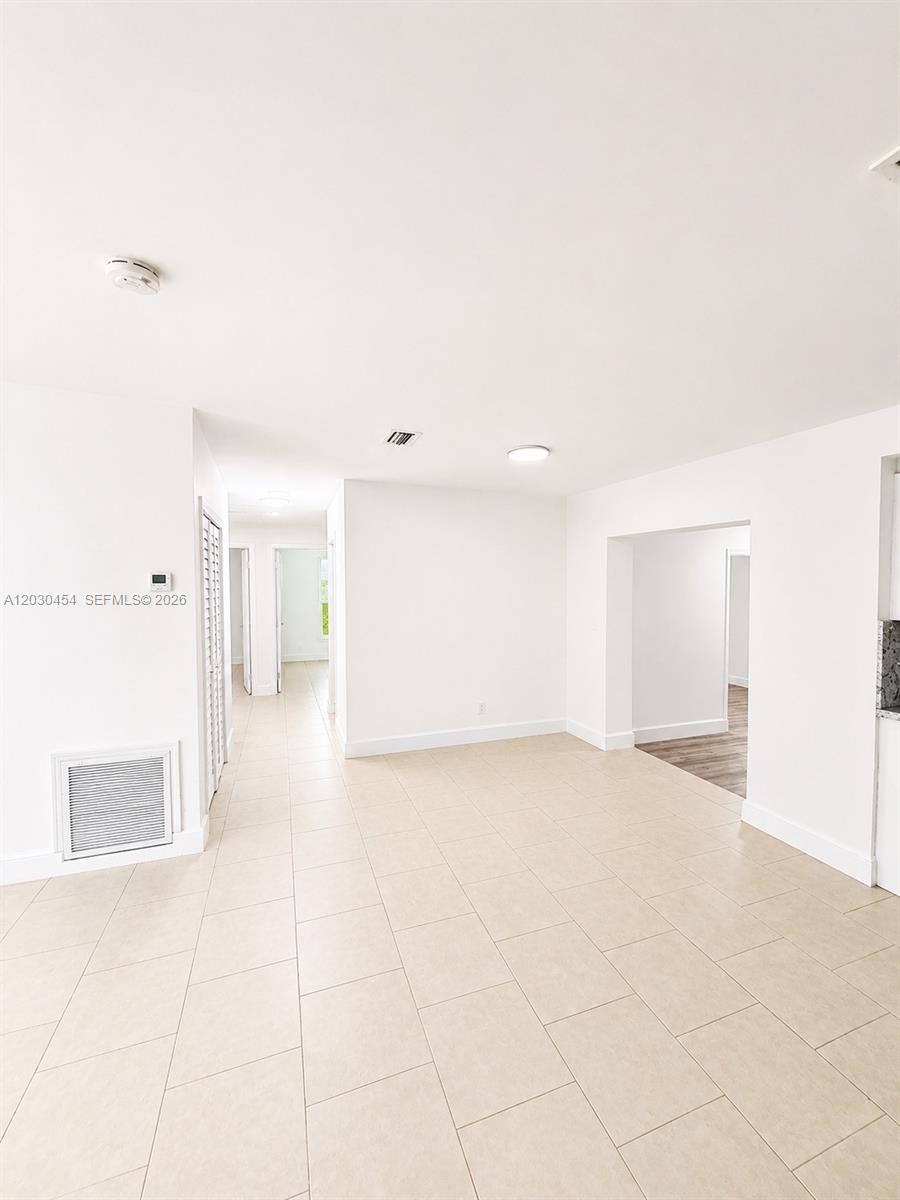 A bright, empty room features white walls, light-colored tile flooring, and a recessed doorway — 20600 SW 118th Pl, Miami FL 33177, MIAMI, FL