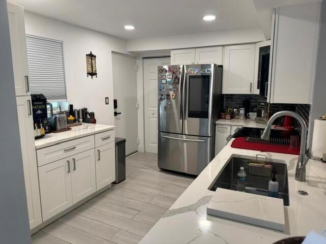 A kitchen with white cabinets, stainless steel appliances, and a quartz-topped island with a sink — 6100 NW 2nd Avenue # 329, Boca Raton FL 33487, BOCA RATON, FL