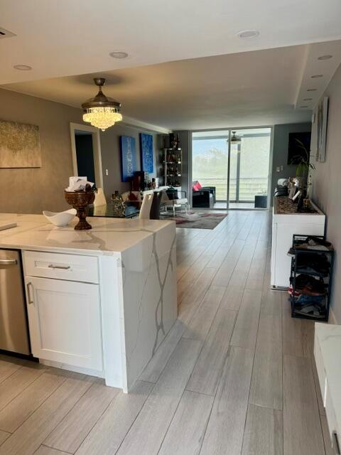 A modern kitchen with a marble-topped island opens into a living area with tile flooring — 6100 NW 2nd Avenue # 329, Boca Raton FL 33487, BOCA RATON, FL