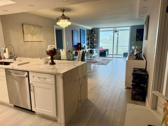 A modern kitchen with a marble-topped island overlooks an open-concept living area with tile flooring — 6100 NW 2nd Avenue # 329, Boca Raton FL 33487, BOCA RATON, FL