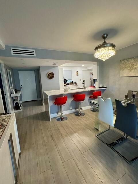 A modern kitchen with a breakfast bar, red stools, and light wood-look tile flooring — 6100 NW 2nd Avenue # 329, Boca Raton FL 33487, BOCA RATON, FL