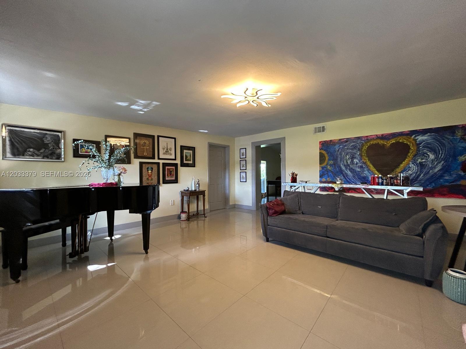 A living room features a grand piano, a gray sofa, and artwork on the walls — 12098 SW 197th Ave, Miami FL 33196, MIAMI, FL