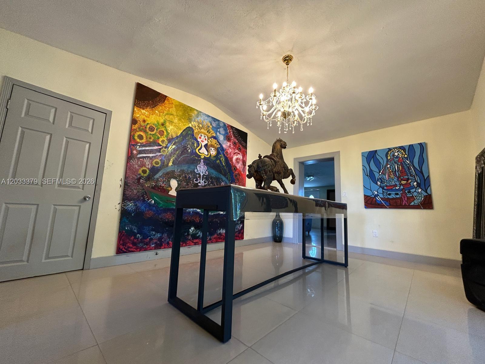 A room features a large abstract painting, a central console table, and a crystal chandelier — 12098 SW 197th Ave, Miami FL 33196, MIAMI, FL