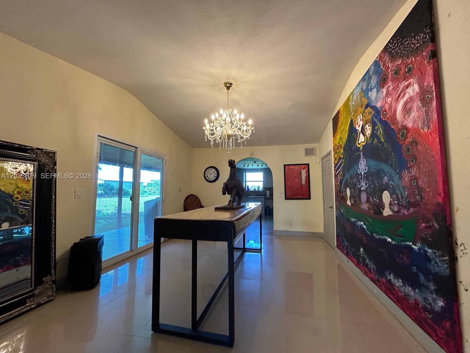 A long table sits in a room with a chandelier, large painting, and glass doors — 12098 SW 197th Ave, Miami FL 33196, MIAMI, FL