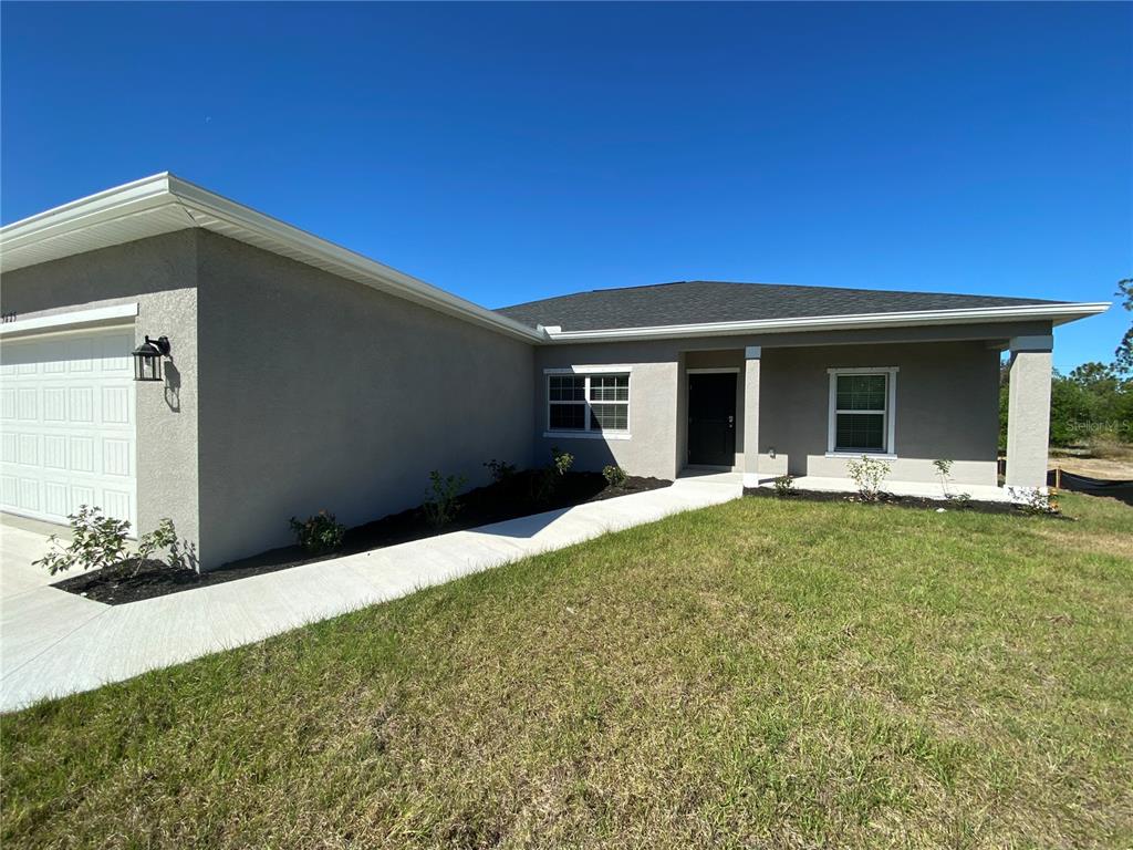 A single-story house with a gray stucco exterior, a white garage door, and a walkway — 5625 ABELMAN ROAD, NORTH PORT, FL