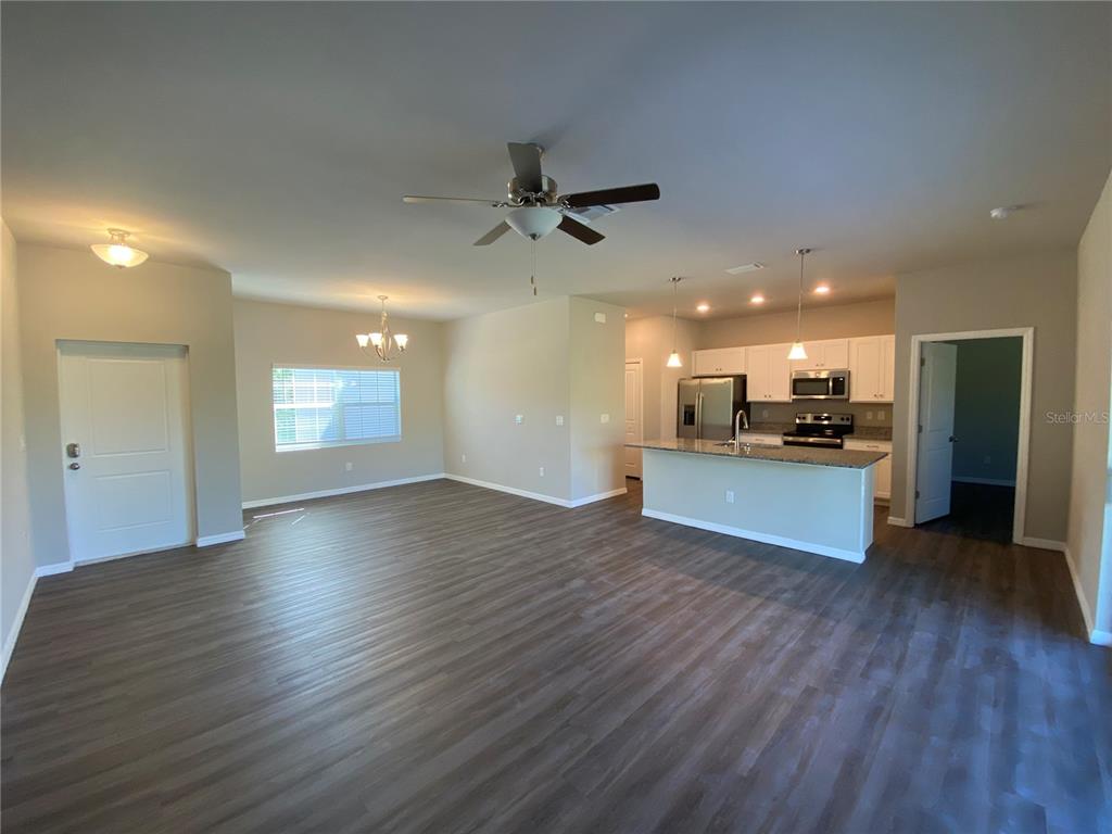 An open-concept living area features wood-look flooring, a kitchen island, and a dining space — 5625 ABELMAN ROAD, NORTH PORT, FL