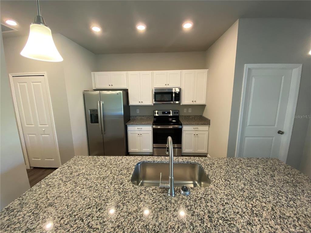 A kitchen features white cabinets, stainless steel appliances, and a granite-topped island with a sink — 5625 ABELMAN ROAD, NORTH PORT, FL