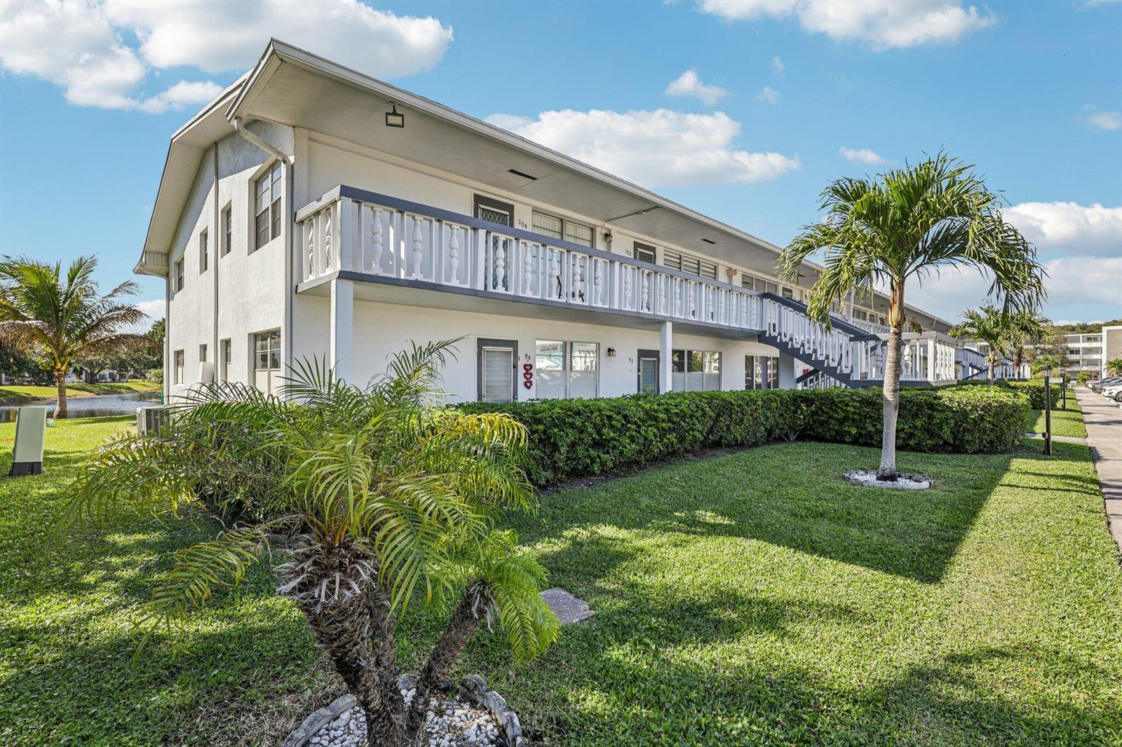 A two-story apartment building with a white exterior, a balcony, and a landscaped lawn — 104 Oakridge # H, Deerfield Beach FL 33442, DEERFIELD BEACH, FL