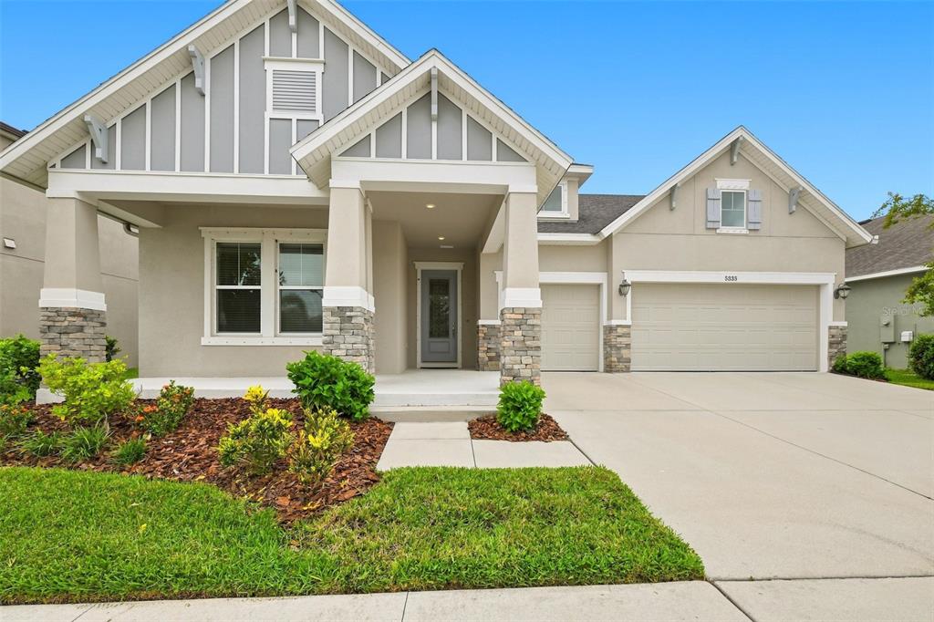 A single-story house with a stone-accented porch, gray siding, and a two-car garage — 5335 SILVER SUN DRIVE, APOLLO BEACH, FL