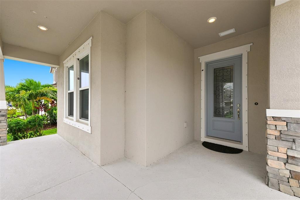 A covered front porch features a light blue front door and stone veneer accents — 5335 SILVER SUN DRIVE, APOLLO BEACH, FL