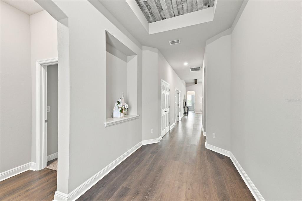 A hallway with light gray walls, wood-look flooring, and a recessed wall niche — 5335 SILVER SUN DRIVE, APOLLO BEACH, FL