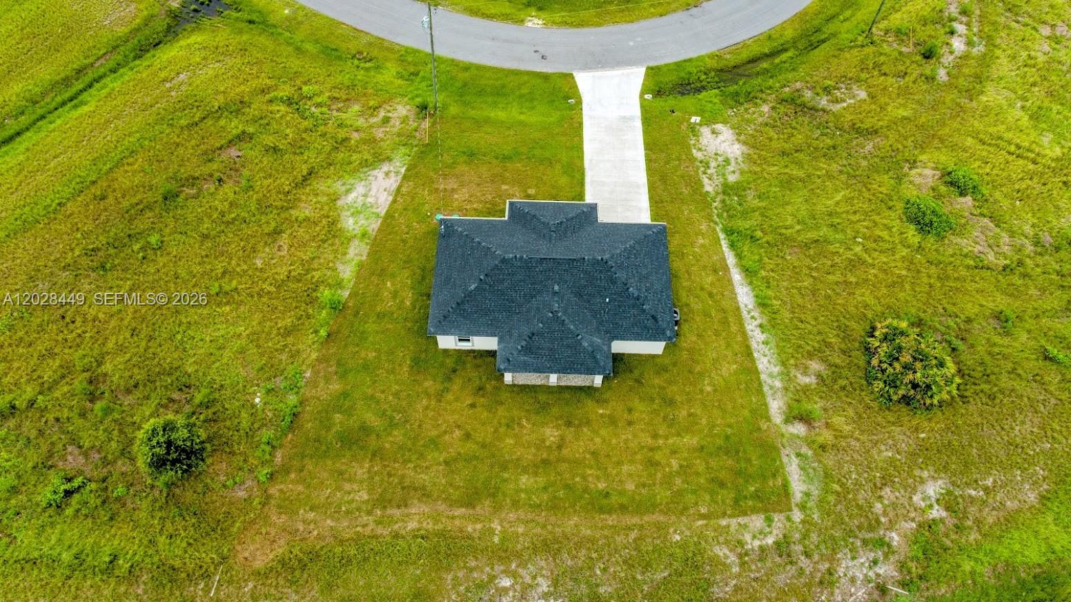 An aerial view shows a single-story house with a dark roof on a grassy lot — 9019 E Crow Cir, La Belle FL 33935, LA BELLE, FL