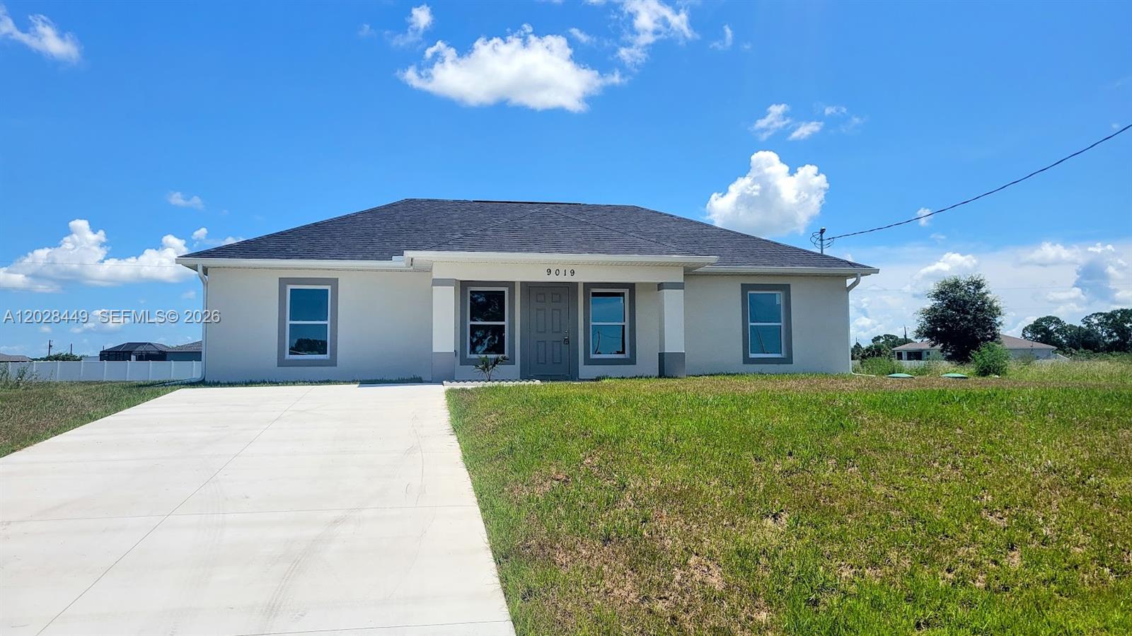 A single-story house with a gray roof, light-colored stucco walls, and a concrete driveway — 9019 E Crow Cir, La Belle FL 33935, LA BELLE, FL