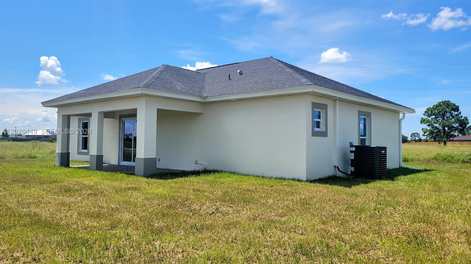 A single-story house with a covered patio, stucco exterior, and a dark shingled roof — 9019 E Crow Cir, La Belle FL 33935, LA BELLE, FL