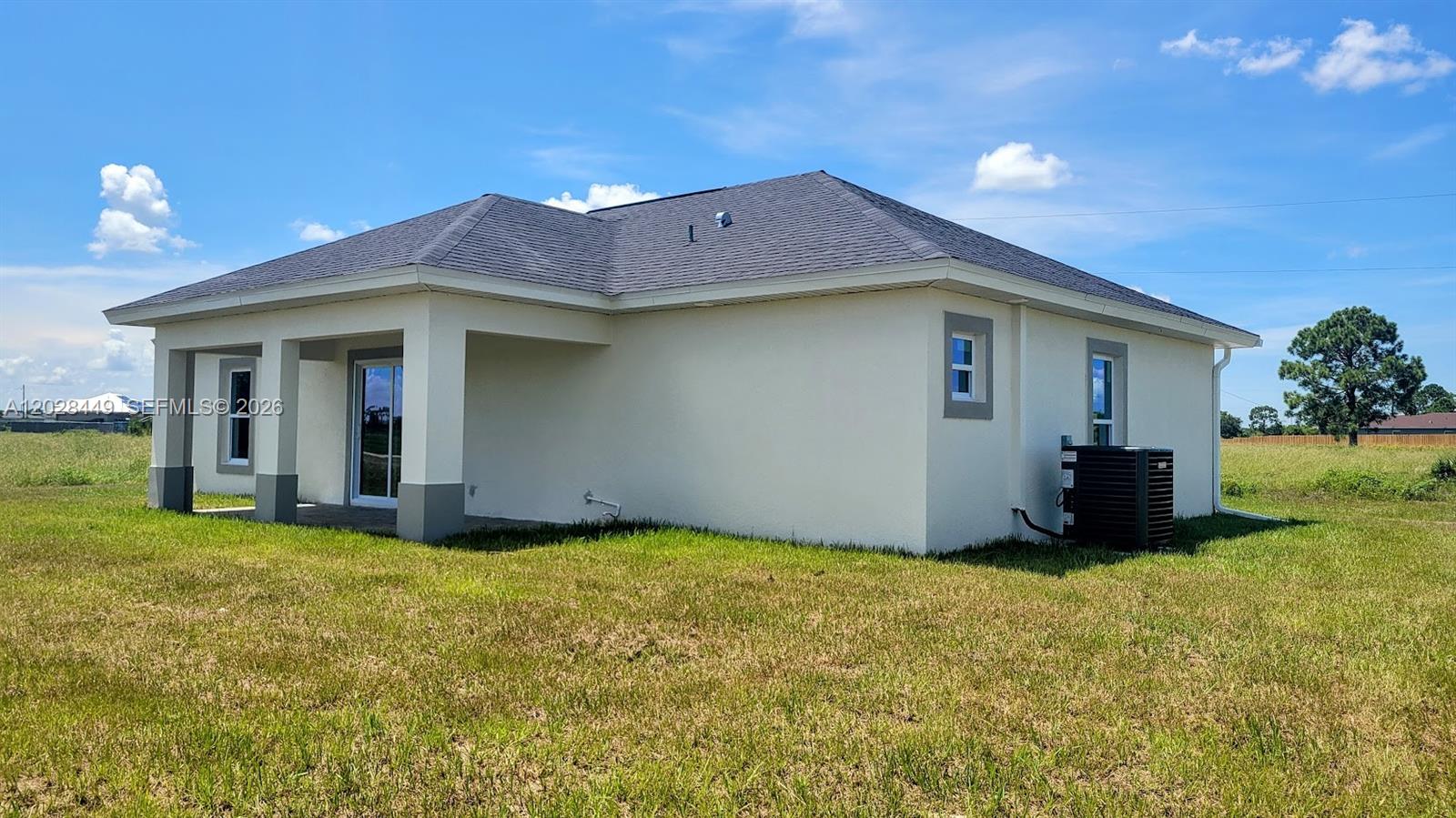 The exterior of a single-story house features a covered patio, stucco walls, and a dark roof — 9019 E Crow Cir, La Belle FL 33935, LA BELLE, FL