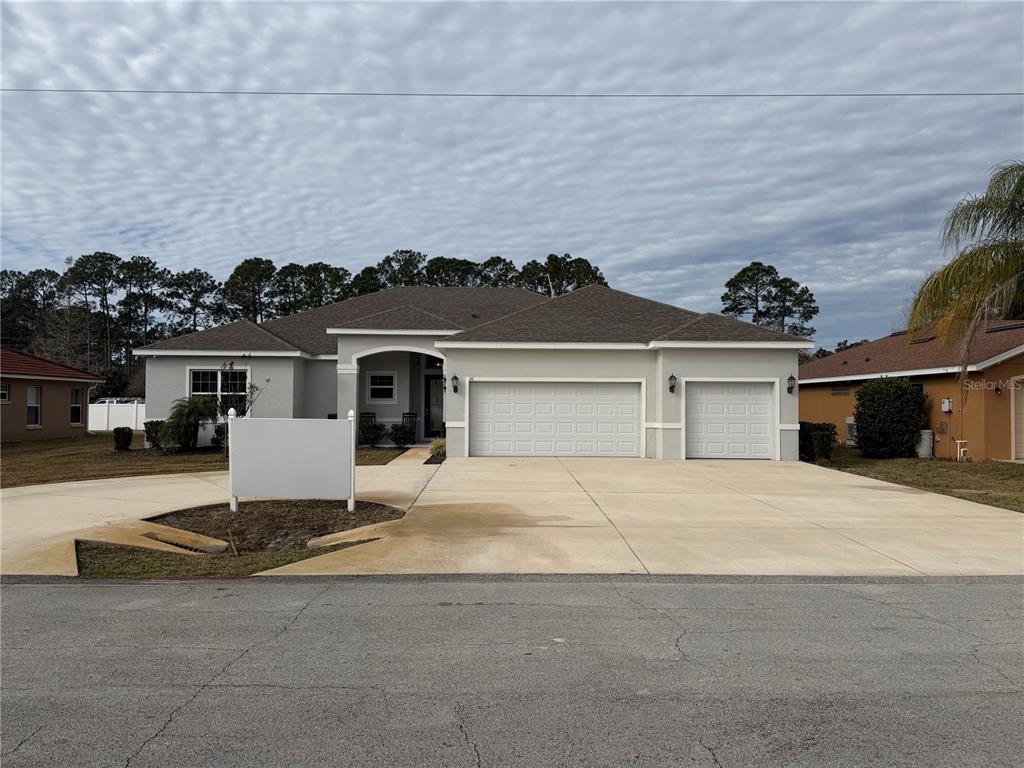 A single-story house with a three-car garage and a large concrete driveway — 10 POINT OF WOODS DRIVE, PALM COAST, FL