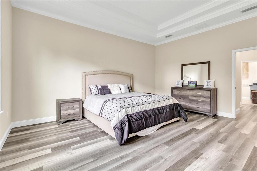 A bedroom features a bed, a dresser with a mirror, and light wood-look flooring — 10 POINT OF WOODS DRIVE, PALM COAST, FL