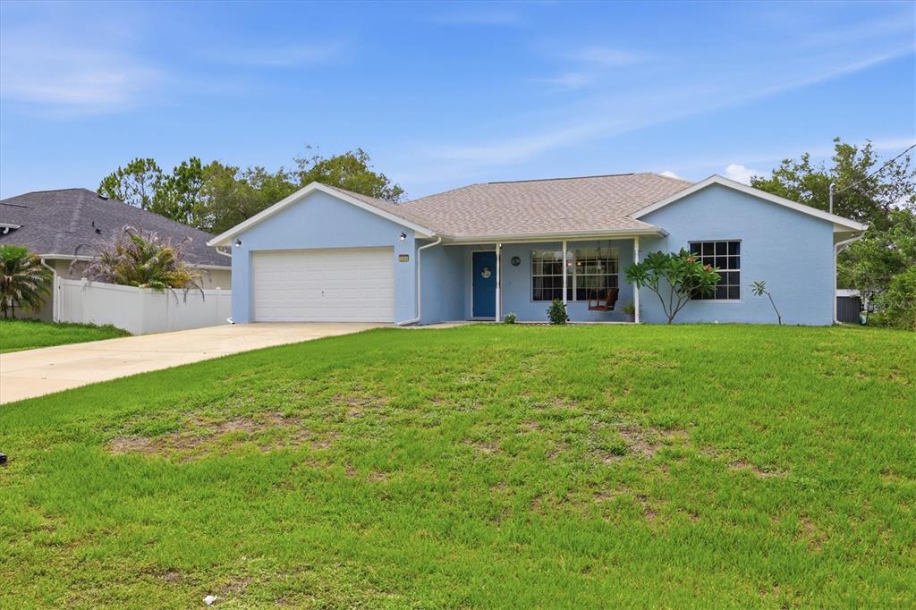 A light blue single-story house features a two-car garage, a front porch, and a lawn — 3265 QUARTER STREET, NORTH PORT, FL