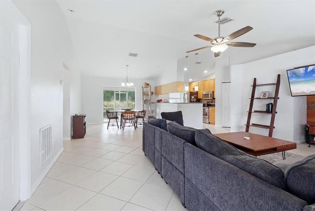 A living room features a large gray sectional sofa, a wall-mounted television, and tile flooring — 3265 QUARTER STREET, NORTH PORT, FL