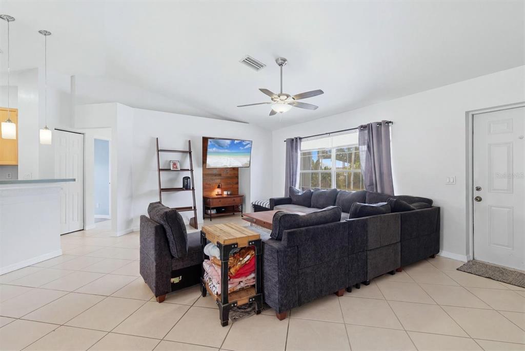 A living room features a large gray sectional sofa, a coffee table, and tile flooring — 3265 QUARTER STREET, NORTH PORT, FL