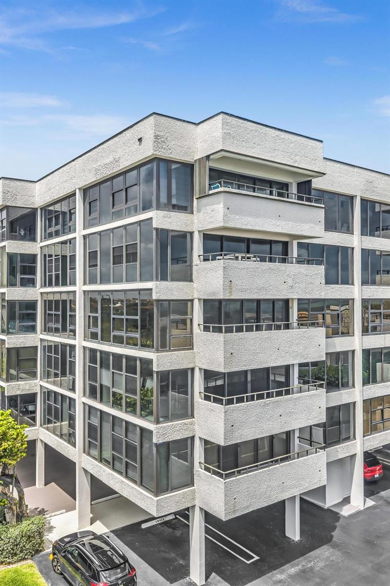 An exterior view of a multi-story apartment building with balconies and a ground-level parking area — 2175 S Ocean Boulevard # 305, Delray Beach FL 33483, DELRAY BEACH, FL