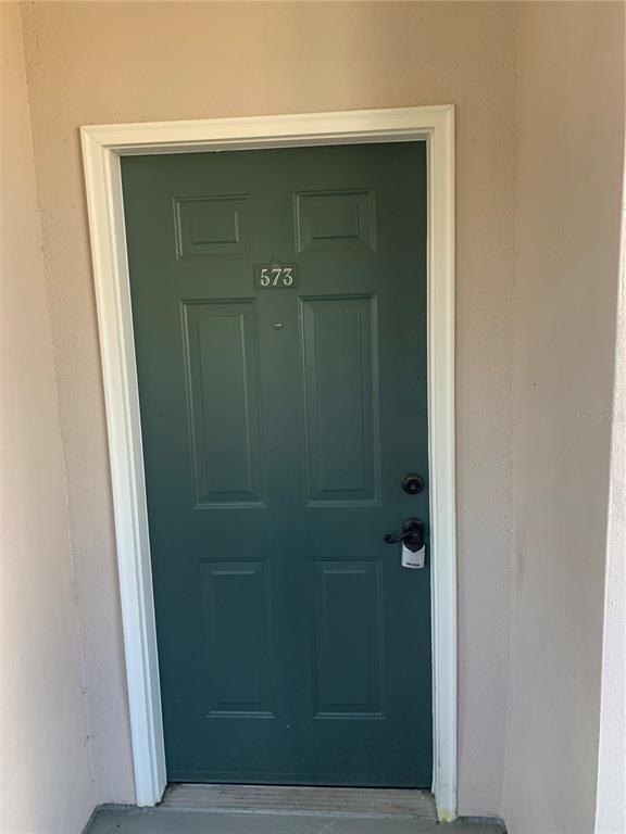 A dark green front door with the number 573 is set within a beige exterior wall — 573 WATER STREET UNIT 573, CELEBRATION, FL