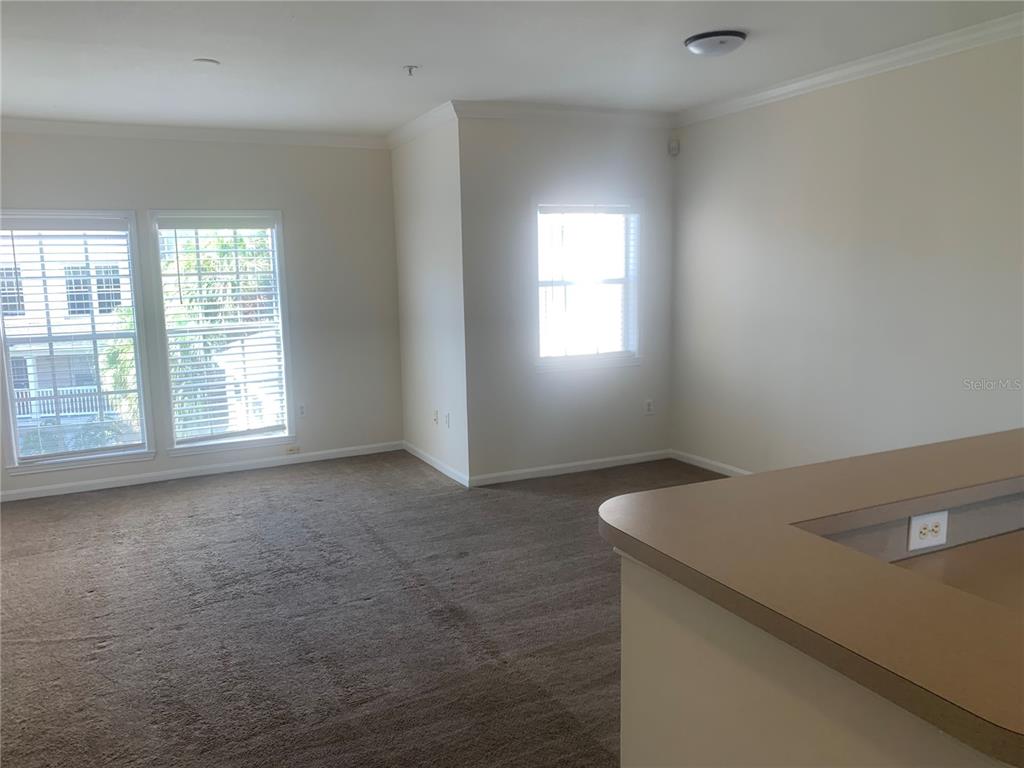 An empty room with beige carpet, white walls, and windows looking out onto a building — 573 WATER STREET UNIT 573, CELEBRATION, FL